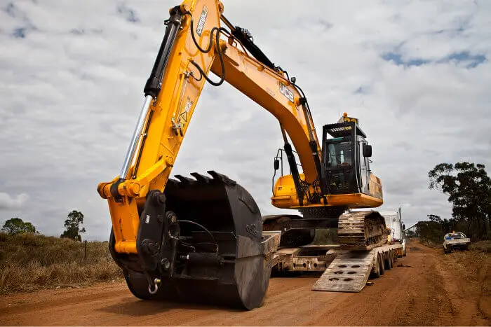 Yellow JCB excavator being unloaded for mining services on a construction site