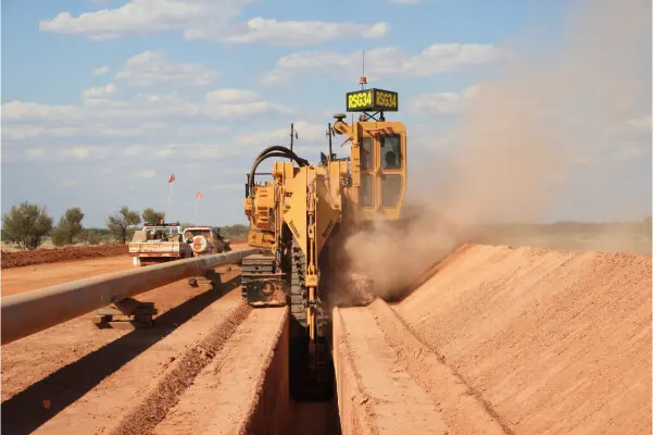 Pipeline trenching machinery at work on a construction site under a clear sky.