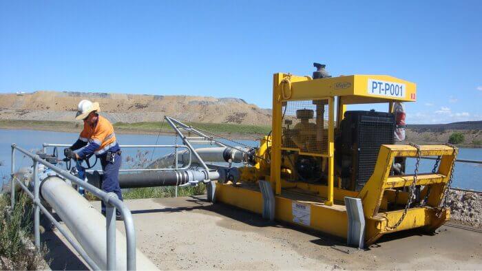 Operator managing a skid pump system for tailing and slurry pipelines near a water source