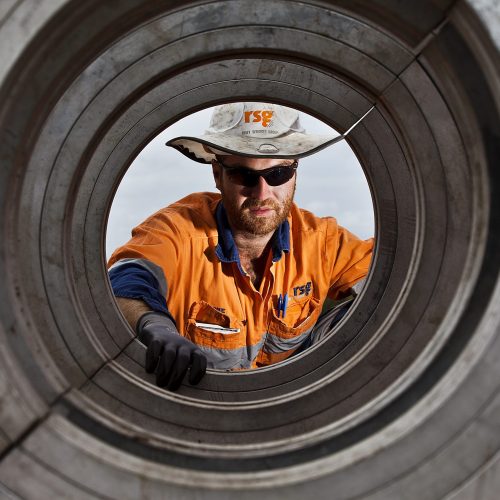 Eigene inspecting a pipeline through a circular pipe opening on a construction site