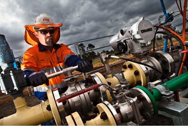 Worker adjusting industrial pipes as part of seam gas drainage services on a cloudy day